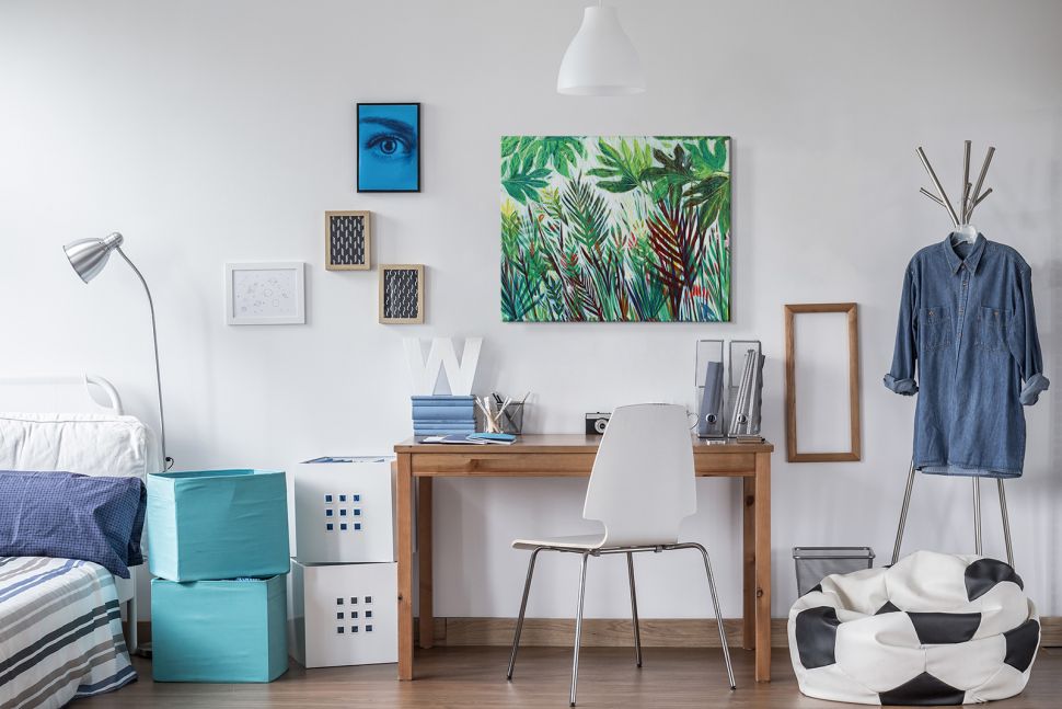 Obraz z widokiem zielonej dżungli powieszony w pokoju nad biurkiem obok obrazka z niebieskim okiem