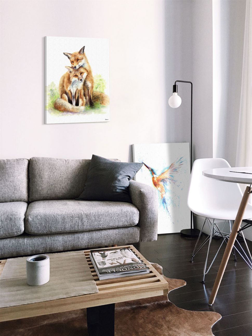 Obraz z zakochanymi lisami w salonie nad szarą kanapą i obrazem z kolorowym kolibrem