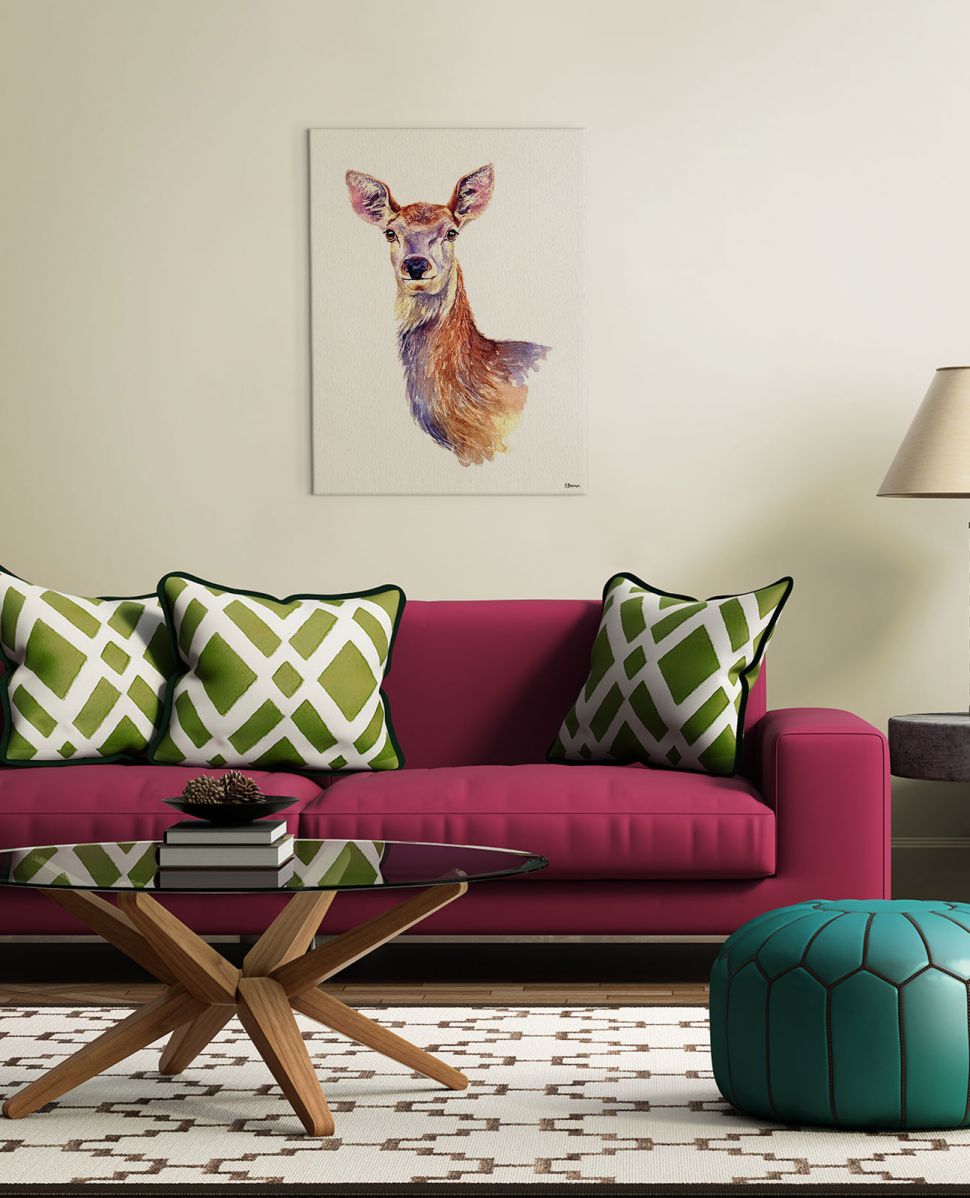 Obraz na płótnie z portretem sarny powieszony w salonie nad czerwoną kanapą z zielonymi poduszkami