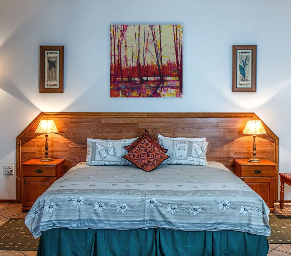 Obraz na płótnie z obrazem przedstawiający kolorowe drzewa powieszony nad drewnianym łóżkiem