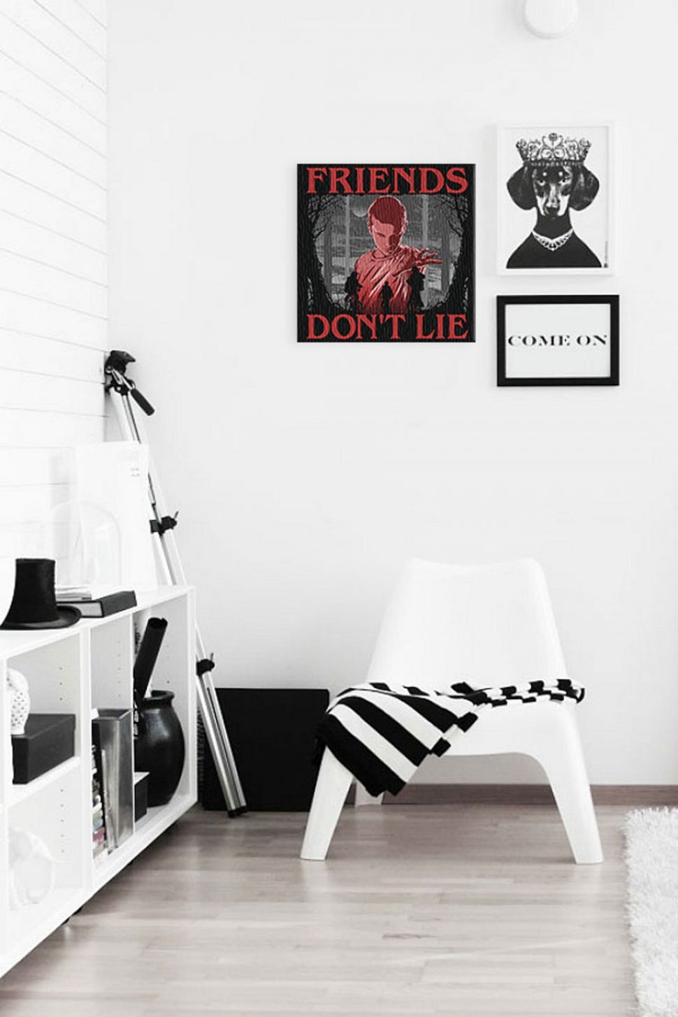 Obraz Friends Don't Lie z jedynastką z serialu Stranger Things zawieszony w pokoju nad białym krzesłem obok obraza z psem w koronie i napisem come on