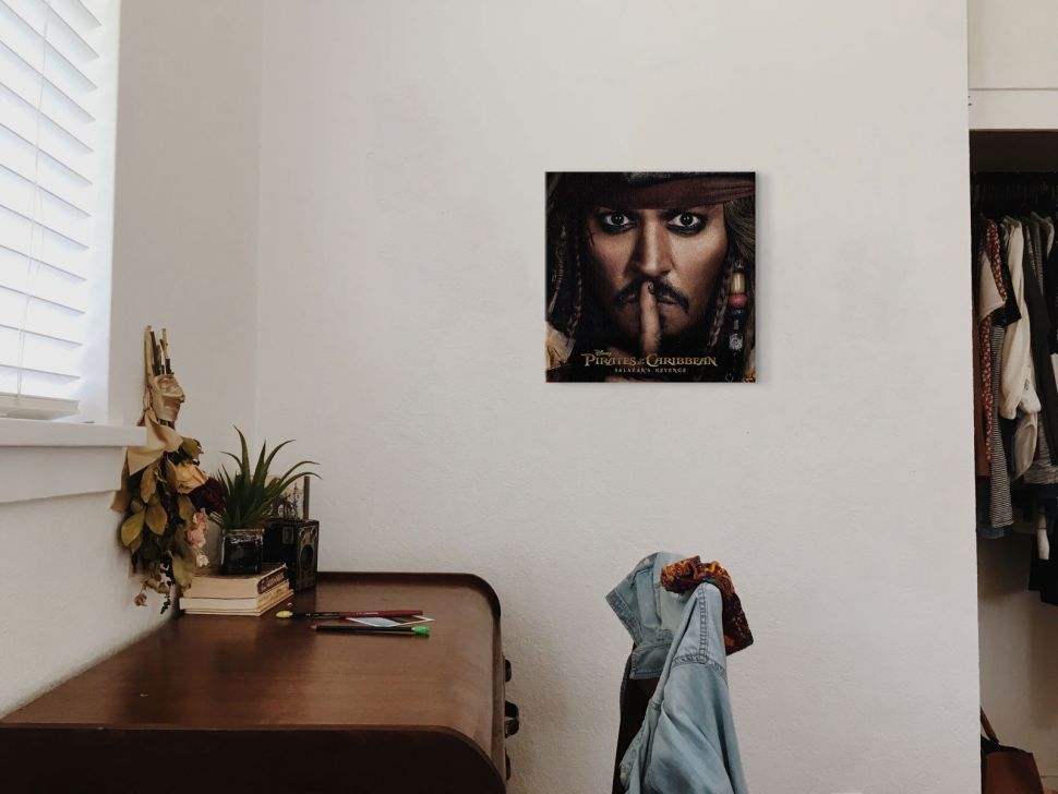 Portret Jacka Sparrowa z filmu Piraci z Karaibów powieszony w pokoju nad fortepianem i krzesłem z dżinsową kurtką