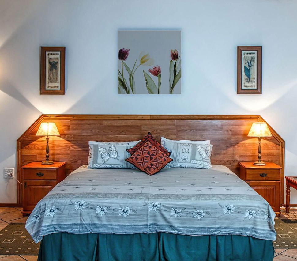 Kolorowe tulipany na obrazie na płótnie powieszonym w sypialni nad drewnianym łóżkiem