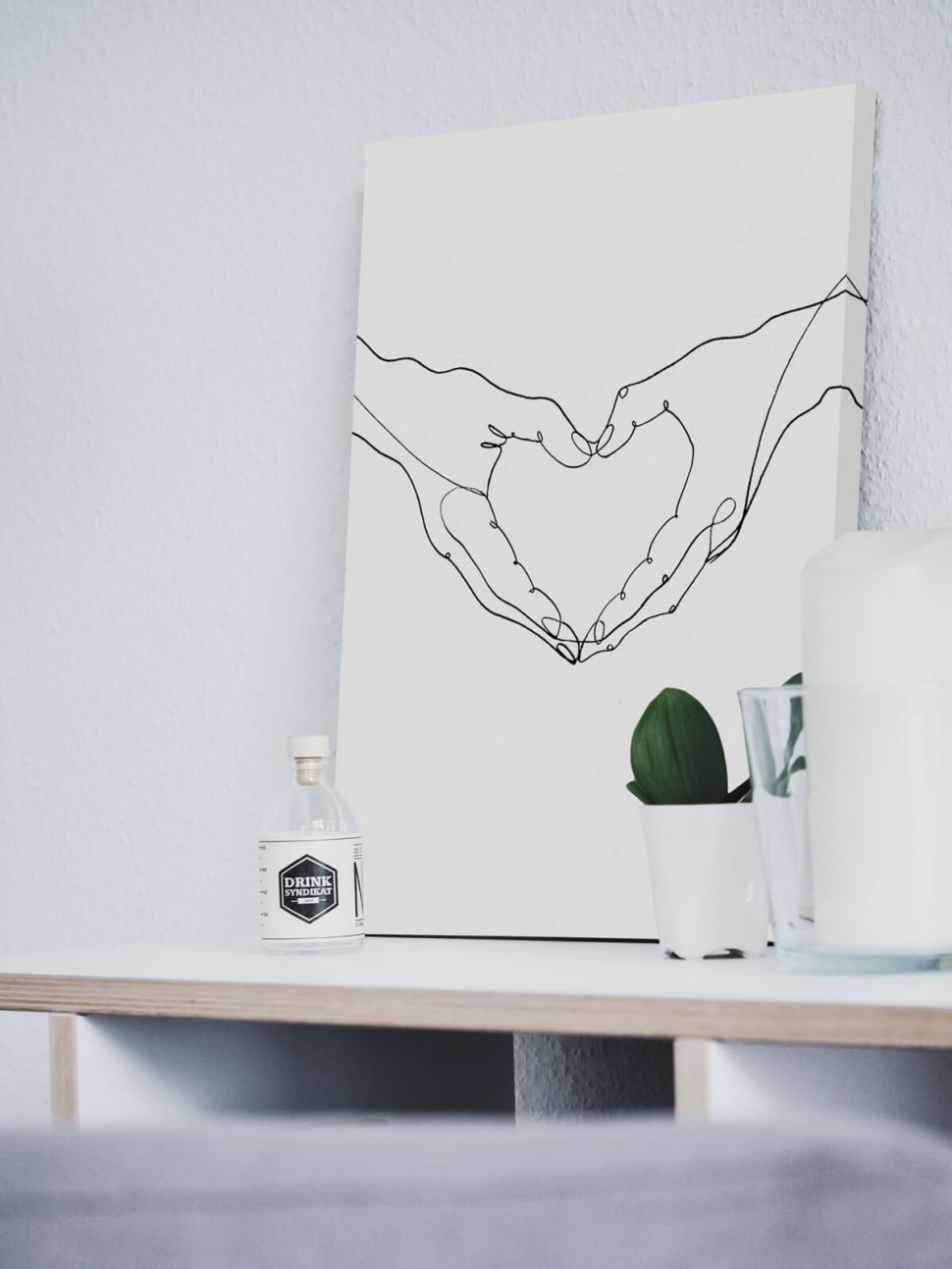 Canvas przedstawiający dłonie ułożone w kształcie serca postawiony na białej szafce