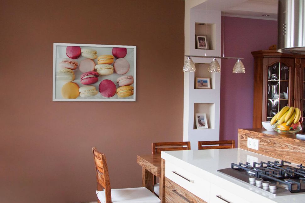 Plakat z makaronikami powieszony na brązowej ścianie w kuchni