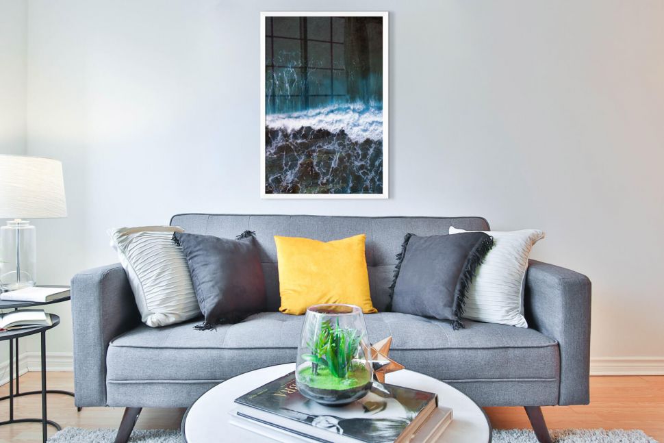 Plakat przedstawiający wzburzone fale przy brzegu powieszony w salonie nad kanapą