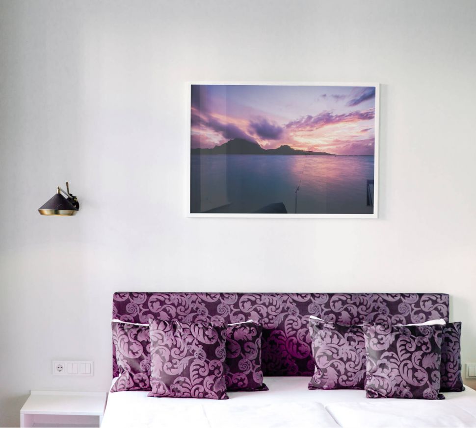 Plakat przedstawiający Zachód Słońca nad jeziorem powieszony w sypialni nad łóżkiem