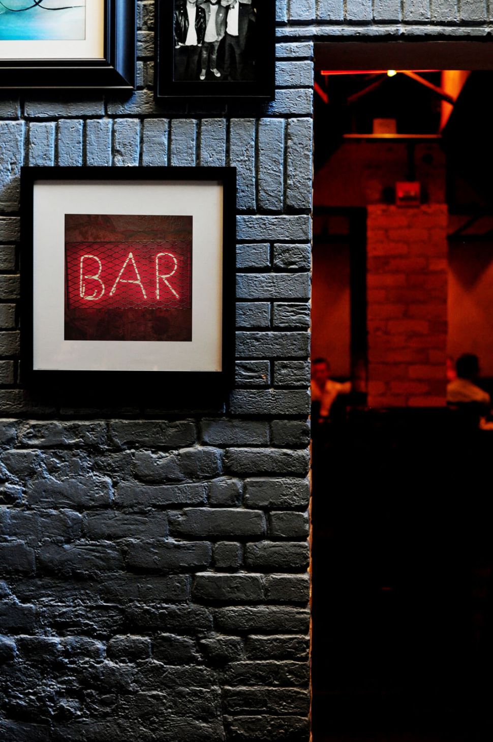 Neonowy napis Bar na reprodukcji powieszonej na ścianie z cegły