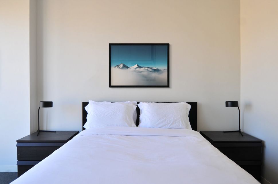 Plakat Górskie Szczyty powieszony nad łóżkiem w sypialni