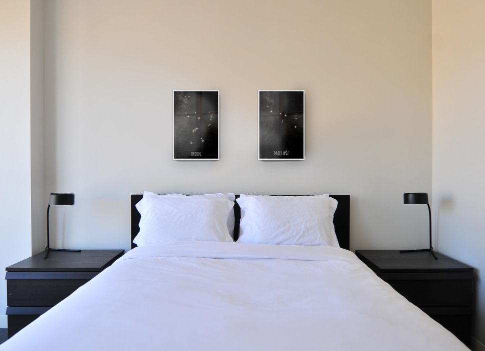 Srebrne ramki aluminiowe powieszone nad łóżkiem w sypialni